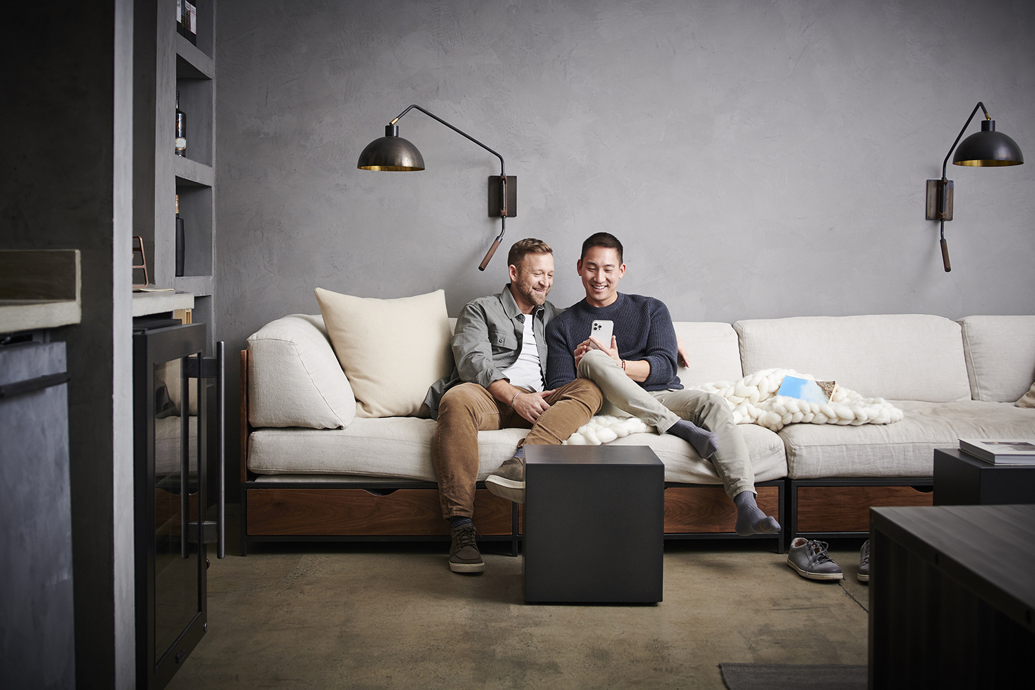 a couple on a couch looking at homes on their cell phone